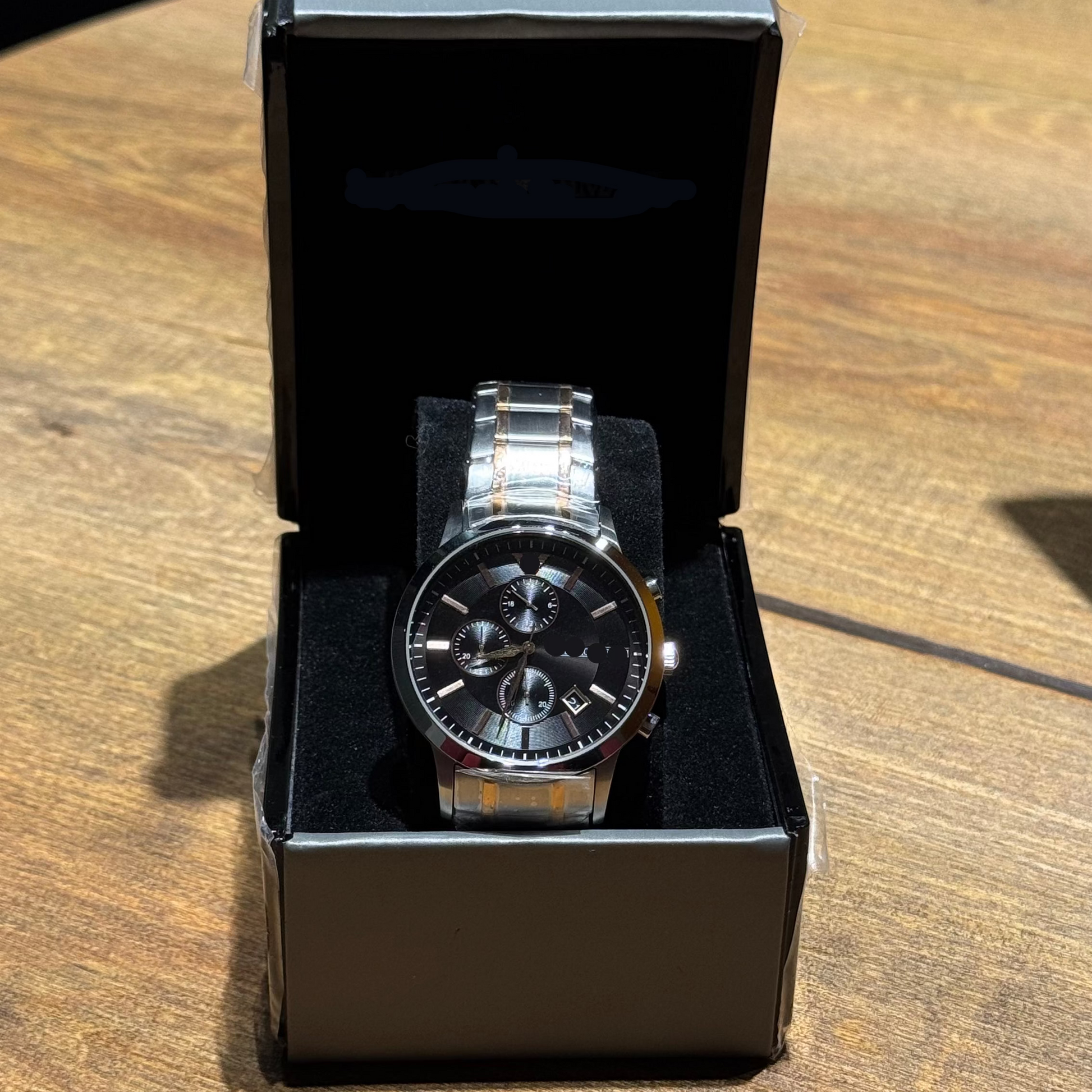 Silver watch in a black box on a wooden surface