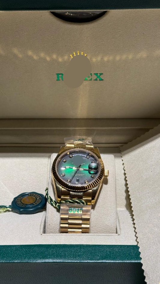 Gold watch with a green face in a Rolex box