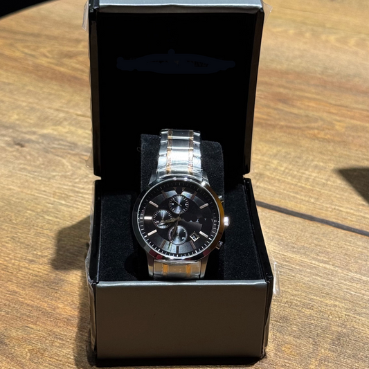 Silver watch in a black box on a wooden surface