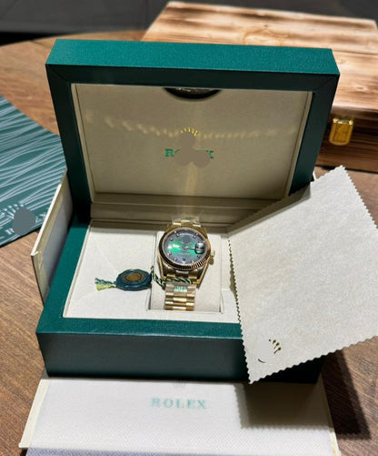 Gold watch in a Rolex box on a wooden surface