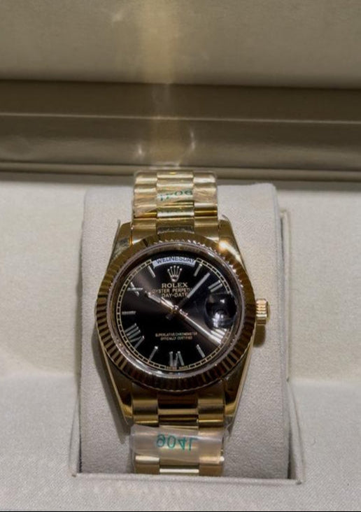 Gold watch with black face in a Rolex box